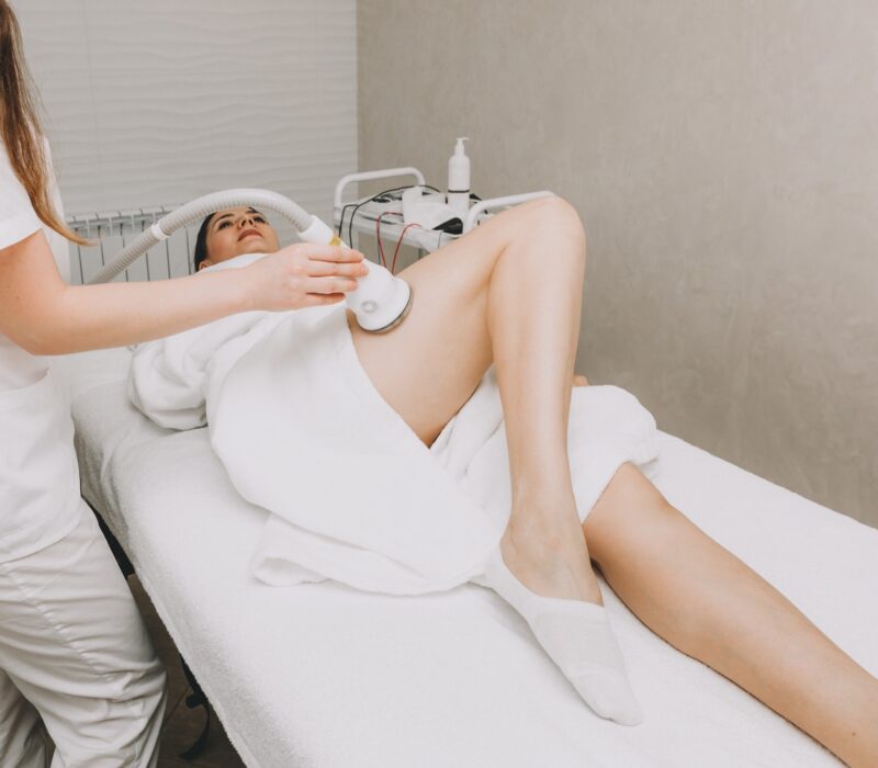 A female beautician holds a nozzle in her hand and leads the client along the thigh and buttocks. RF lifting procedure in the spa.