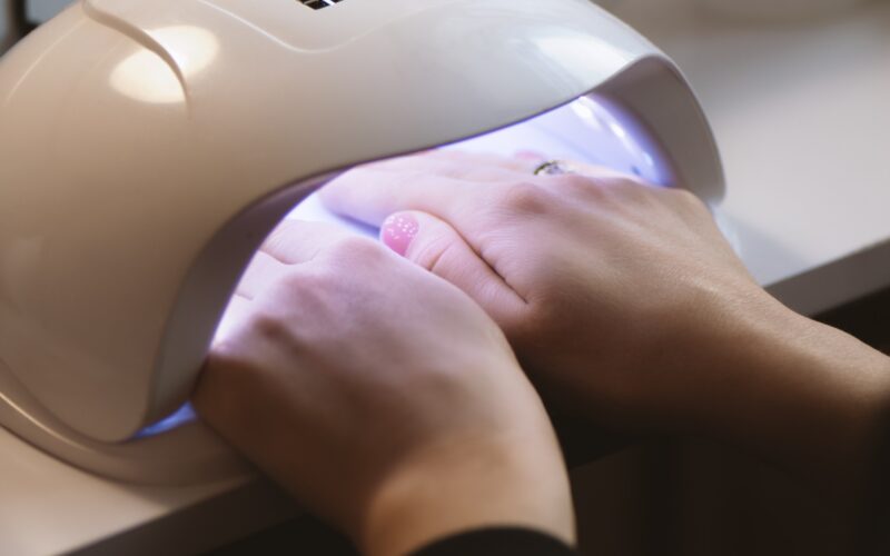 Manicurist doing gel nail design for client, close up